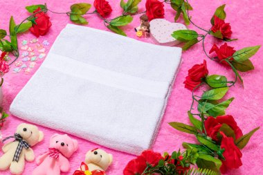 Sevgililer günü temalı dekorasyonlarla çevrili yumuşak pembe bir halının üzerinde beyaz boş bir havlu.
