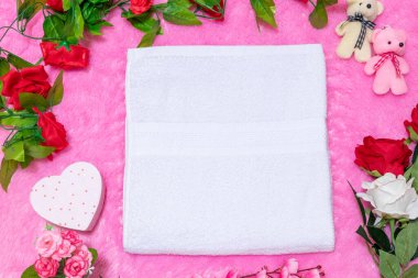 Sevgililer günü temalı dekorasyonlarla çevrili yumuşak pembe bir halının üzerinde beyaz boş bir havlu.