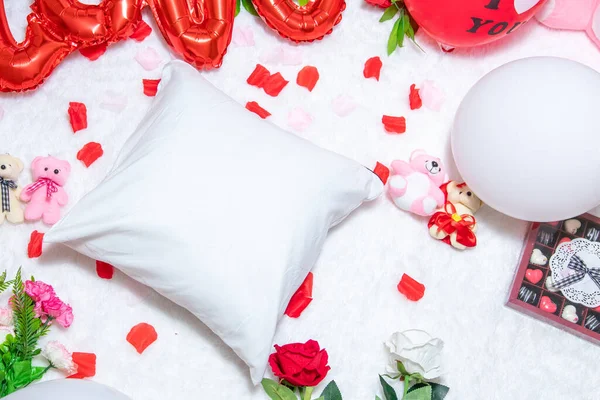 White blank pillow above a a fluffy white carpet surrounded by valentine themed decorations