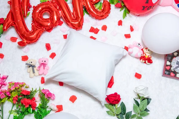 White blank pillow above a a fluffy white carpet surrounded by valentine themed decorations