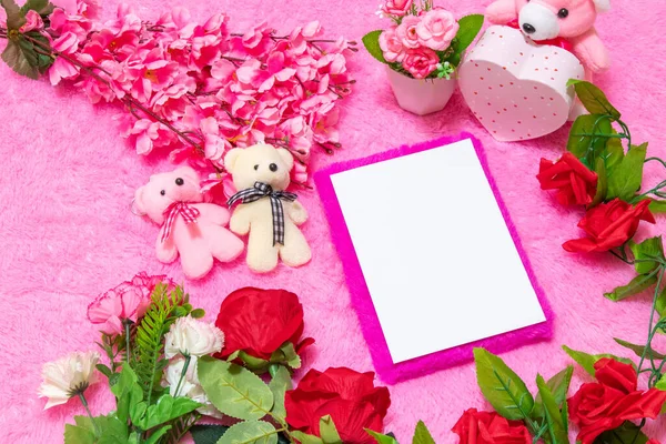 Sevgililer günü temalı dekorasyonlarla çevrili pembe kaplı bir defterin üzerinde beyaz, boş bir defter ve arka plan olarak da pembe, tüylü bir halı.