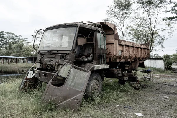 Side view of a broken old truck that has been badly damaged, abandoned in the middle of a park with scary vibes