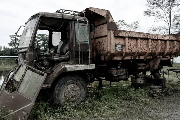 Side view of a broken old truck that has been badly damaged, abandoned in the middle of a park with scary vibes