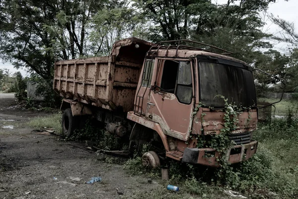 Side view of a broken old truck that has been badly damaged, abandoned in the middle of a park with scary vibes