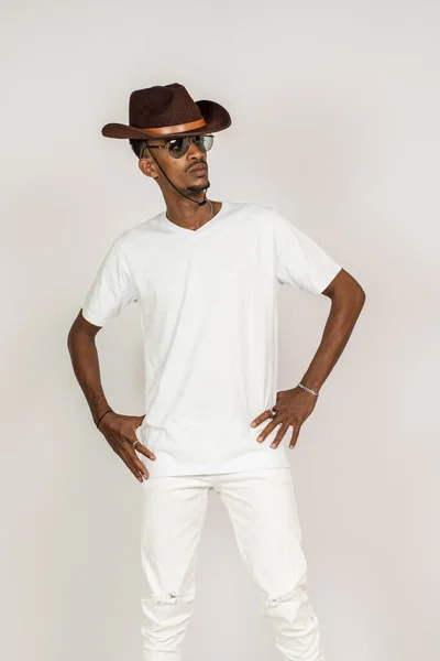 An african man with v-neck shirt doing a pose while touching his waist and facing sideways, on the white background