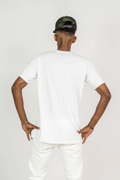Back side of an african man with white shirt doing a pose while touching his waist on the white background