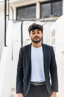 Sakallı genç bir adam beyaz gömleğiyle poz veriyor. Dışarıdaki takım elbisesi gibi. Sahte beyaz gömlek.