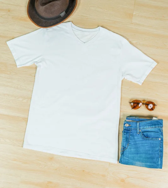 A v neck shirt laid out on the top of the wooden tiling, with a jeans and a glasses near it, minimalistic decoration