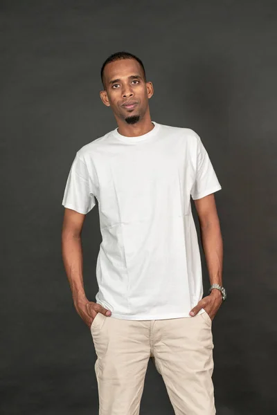Mockup image of an african man wearing a white blank shirt doing a pose, on the black background