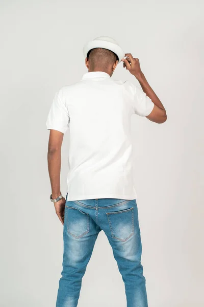 Back side of an african man with polo shirt doing a pose while touching his hat, with white background mockup image