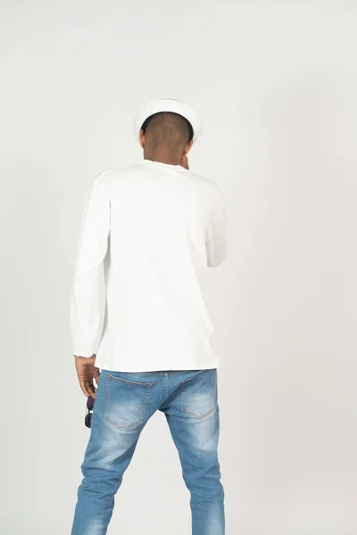 Back side of an african man with blank white shirt and a hat doing a pose, on the white background
