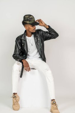 Beyaz, boş gömlekli, deri ceketli, beyaz arka planda, poz veren Afrikalı bir adam.