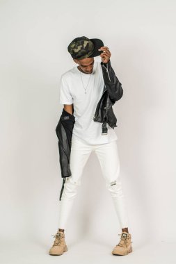 Beyaz, boş polo ve deri ceket giyen Afrikalı bir adam beyaz arka planda poz veriyor.