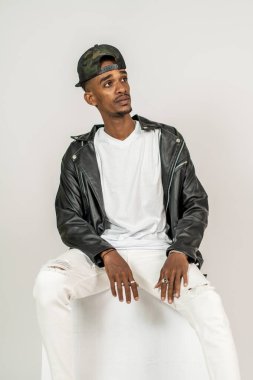Beyaz, boş gömlekli, deri ceketli, beyaz arka planda, poz veren Afrikalı bir adam.