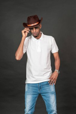 Siyah arka planda beyaz, boş, şapka ve gözlüklü, poz veren Afrikalı bir adam.