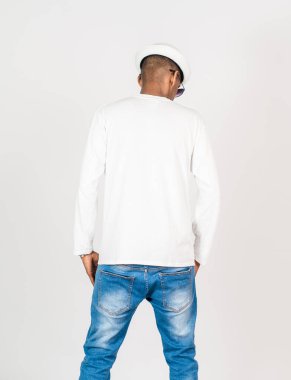 Beyaz, boş, uzun kollu gömlekli, gözlüklü ve şapkalı beyaz arka planda poz veren genç bir adamın arkası.