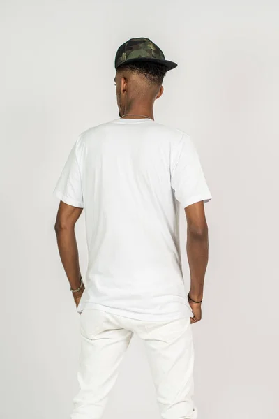 Back side of an african man wearing white blank shirt and a hat doing a simple pose, on the white background