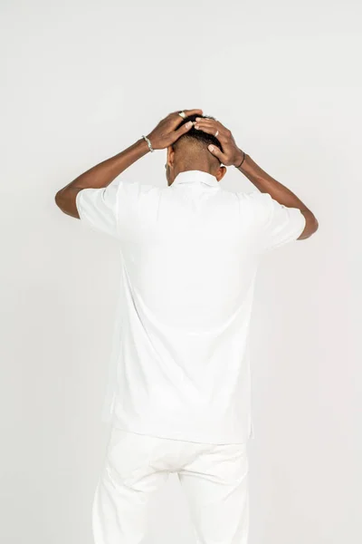 Back side image of an african man wearing white blank polo shirt, doing a pose with both of his hand on his head, on the white background