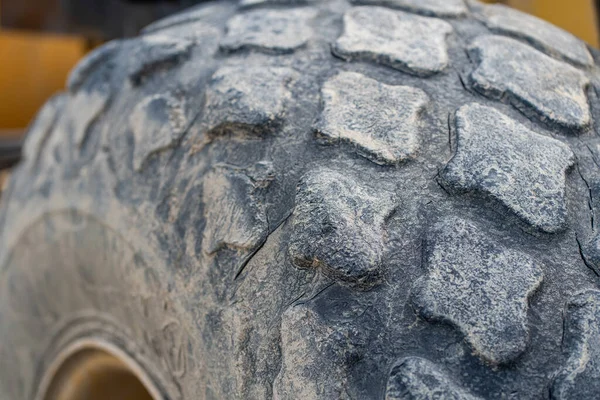 The part of big black tire of a compactor that has been covered in mud, taken in the mid day