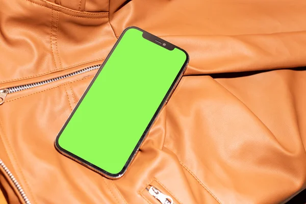 Green screen smartphone image on the top of a brown leather cloth, minimal concept