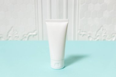 A standing white colored cream bottle laying out on the top of a blue paper, bottle mockup template image