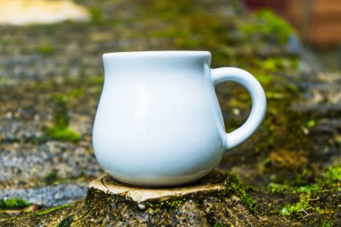 A caramel mug standing out of a top man made tree stump, caramel mug mockup image