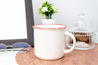 A white blank enamel mug on the top of a rounded mat decorated with minimalistic style, enamel mug mockup image