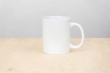 A white blank coffee mug on the top of a plywood with a clean white background behind it, coffee mug mockup image