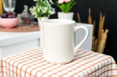 A white blank coffee mug on the top of a hand cloth with simple decorations arranged around it, coffee mug mockup image