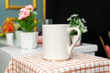 A white blank coffee mug on the top of a hand cloth with simple decorations arranged around it, coffee mug mockup image