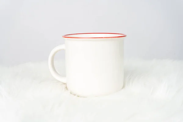 A white blank enamel mug on the top of a white table with the white background, enamel mug mockup image
