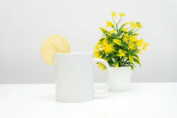 A white blank coffee mug with a slice of lemon decorated to the edge of the mug, minimalist fresh concept, coffee mug mockup image