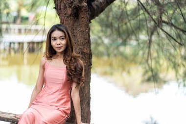 Pink-clad woman basks in park's bokeh beauty, with negative space for copy