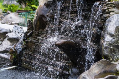 The small fountain, delicately flowing into the tranquil pond, adds an enchanting touch to any outdoor setting and creates a peaceful ambiance