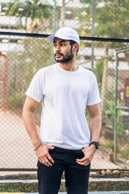 Temiz beyaz gömlek ve şapka kombinasyonu bu sakallı adam için cesur ve şık bir görünüm yaratır, onu ilgi odağı yapar, beyaz boş şapka ve gömlek modeli imajı.