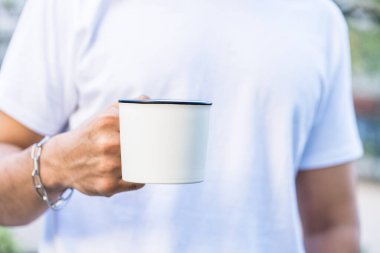 Basit ama çarpıcı bir fotoğraf, beyaz, boş bir kupa şeklindeki resmi tutan bir eli gösteriyor.