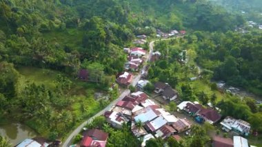 Burada ve orada kırılan küçük bir yolun ve etrafında bir dron tarafından alınan küçük bir köyün görüntüsü.