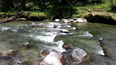 Hava görüntüleri, pürüzlü kayaların etrafında gezinirken suyun huzurlu dansını gözler önüne seriyor.