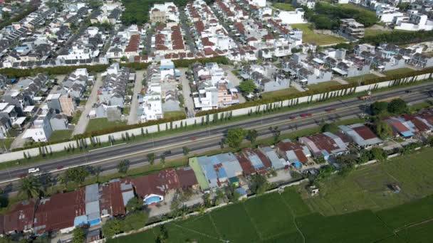 ドローンで撮影された住宅団地の隣の忙しい道路に焦点を当てた都市の街並み空撮 — ストック動画