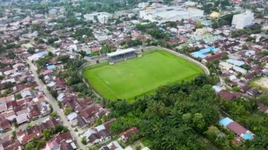 Evlerle çevrili bir stadyumun hava görüntüleri, insansız hava aracı tarafından eğik bir hareketle çekildi.