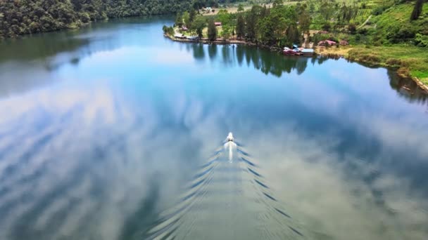 後方の動きを持つボートに焦点を当てドローンで撮影された湖の上に動く白いボートを示す空中映像 — ストック動画