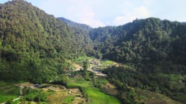 Ortasında insansız hava aracı olan küçük bir köyün bulunduğu bir tepenin hava görüntüleri.