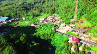 Etrafına küçük bir köy inşa edilmiş bir yolun hava görüntüleri, bir dron ile çekilmiş.