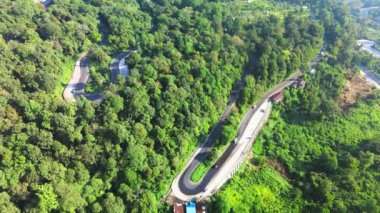 Uçağı ile çekilen bir tepenin üzerindeki eğri yolu gösteren hava görüntüleri.