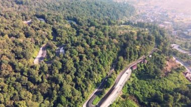 Yoğun araç aktivitesi olan bir tepenin üzerinde insansız hava aracı ile çekilmiş kavisli bir yol görüntüsü.