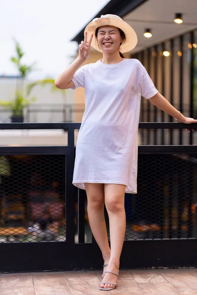 Güzel bir Asyalı kadın fotograf için nefes kesici bir yerde poz veriyor. Gömlek modeli bir resim.