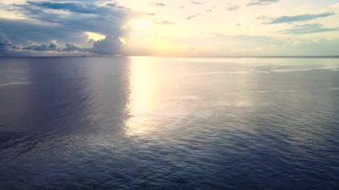 Önünde altın güneş ışığı olan sakin okyanusun insansız hava aracı ile çekilmiş görüntüleri.