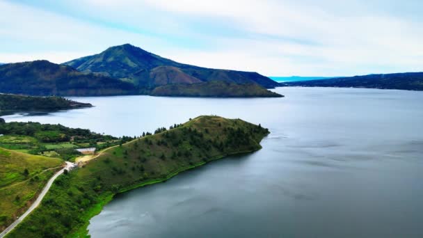 丘や道路を持つ大湖の静物画を公開する空中ショットを魅了する調和のとれた風景を作り出す — ストック動画