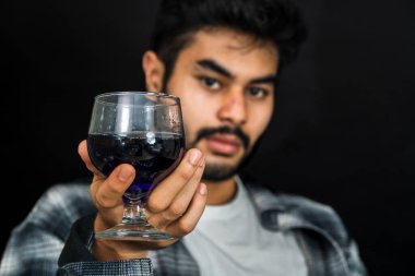 Görsel olarak büyüleyici bir görüntü elinde mor renkli bir içecek tutan bir adamı gösteriyor. Görsel sunumlarınız için büyüleyici bir sahne yaratıyor.