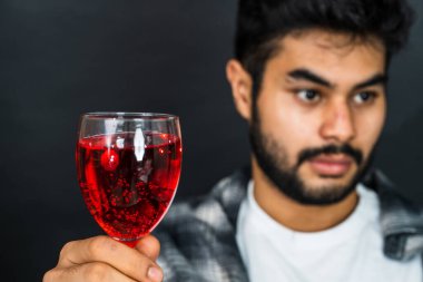 Sanatsal olarak bestelenmiş resimde elinde kırmızı renkli bir içki olan bir adam var ve sahneye cazibe katıyor.